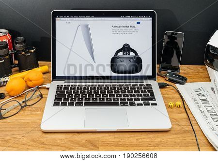 PARIS FRANCE - JUNE 6 2017: Apple Computers website on MacBook Retina in creative environment showcasing latest news from Apple at WWDC 2017 - VR mask next ot imac computer