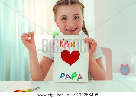 girl surprising parents with greeting card at home