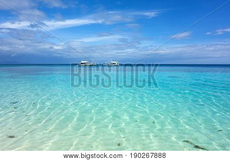 White clouds and Banca boat on blue sky over calm sea. Clear blue water with fantastic white sand beach. Summer outdoor nature holiday serenity. Kalanggaman Island Philippines. Background copy space.