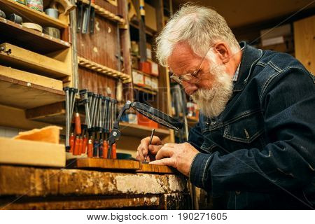 Senior wood carving professional during work