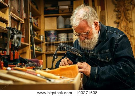 Senior wood carving professional during work
