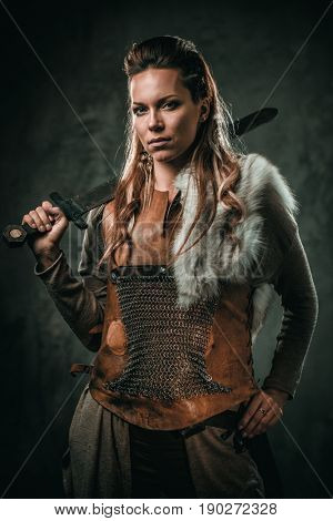 Viking woman with cold weapon in a traditional warrior clothes