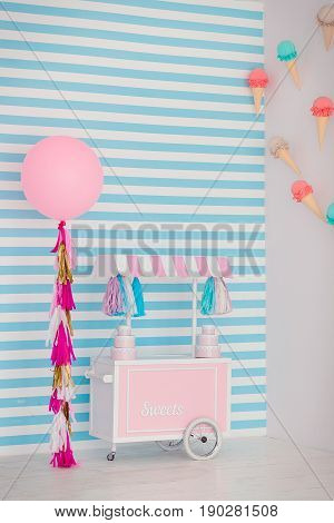 Children's zone with sweets: lollipops, ice cream, macarons, balloon and candy bar. Children room with blue stripe background.