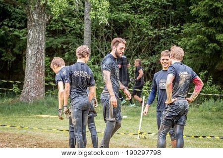 Stockholm Sweden - June 03 2017: Rear view group of dirty caucasian male athletes talking and resting after completing a mud obstacle at the annual event Toughest Stockholm.