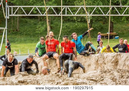 Stockholm Sweden - June 03 2017: Front view group of caucasian people struggling in an mud obstacle to complete the course of the annual event Toughest Stockholm.