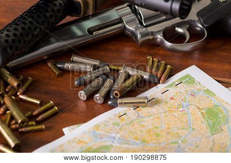 Bullets and a firearm. Bullets are a projectile expelled from the barrel of a firearm over a map, on wooden table.