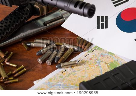 Close up of a shotgun and a revolver, cartridge belt with bullets with North Korean flag on a map, on wooden table.