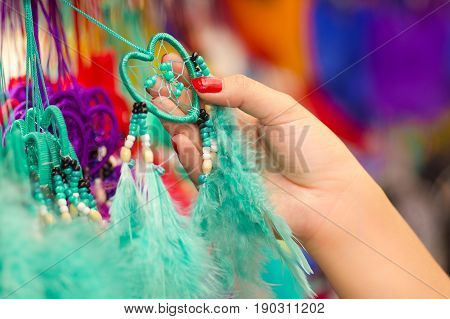 OTAVALO, ECUADOR - MAY 17, 2017: Close up of a woman holding a magenta catchdreamer in her hand, in colorful market background.