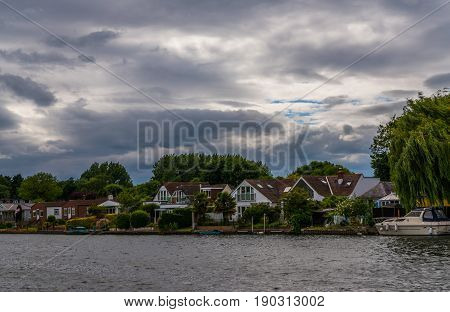 View Of The Other Side Of The River, Residential Houses Located On The Shore, Beautiful Boats, Lush