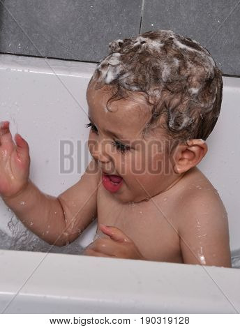 Shampoo head baby portrait at bath tub.