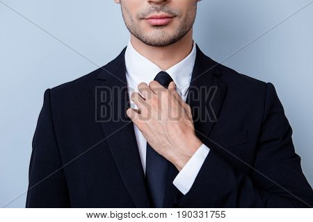 Close Up Cropped Portrait Of Young Handsome Businessman Lawyer In Suit. He Is Fixing His Tie. He Sta