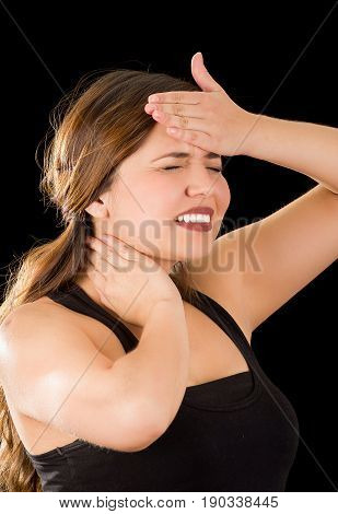 Close up of a beautiful young lady Suffer crick after workout with a hand in her forehead, in a black background.