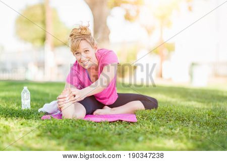 Young Fit Flexible Adult Woman Outdoors on The Grass With Yoga Mat Stretching Her Legs.