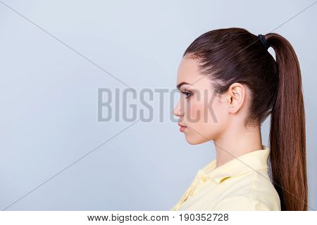 Close Up Cropped Profile Portrait Of Young Lady In Yellow Tshirt With Ponytail, Serious Face On Pure