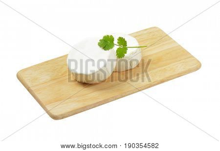 Two wheels of soft white cheese on cutting board