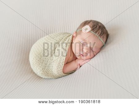 Adorable kid napping wrapped with a scarf, arm hanging out of it, sleeping tight