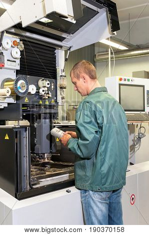 Worker- repairman operating industrial cnc machine in workshop. Metalworking and engineering industry lathe cnc and milling technology.