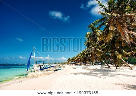 Tropical beach with palm trees pilippine boats blue sky turquoise water and white sand. Paradise. Philippines Boracay. Wide angle horizontal