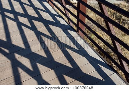 Shadow patterns of wooden and handrail bridge.