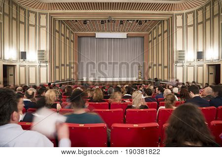 Theather stage with people silhouette at the foreground.