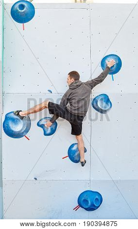 man climber climbs a bouldering problem on climbing gym. man mekes hard wide move. Climbing competition