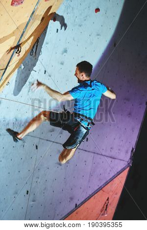 man climber climbs with rope on climbing gym. man mekes hard wide move and falling. Climbing competition