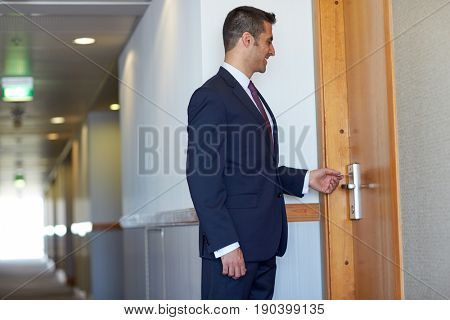 business, security and people concept - businessman with keycard at hotel room or office door
