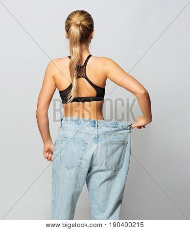 fitness, diet, weight loss and people concept - young slim sporty woman in oversize pants