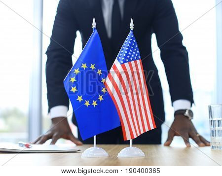 American flag and flag of European Union with businessman near by