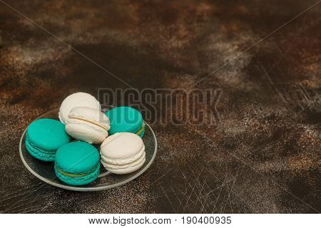 Cake macaron or macaroon on brown background teal and white almond cookies on plate copyspace