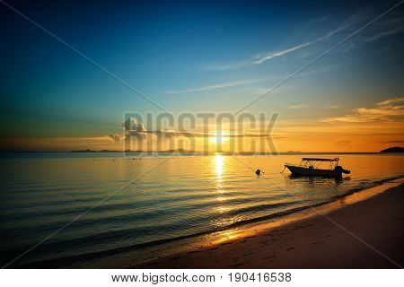 Golden dawn over the beach silhouette speed boat .Rawa island Malaysia . Selected focus on center .