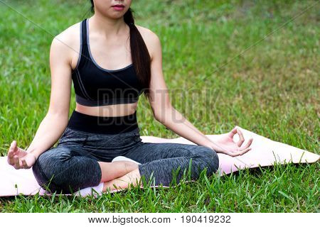 woman meditation sit on the yoga matt outdoor near grass and nature view
