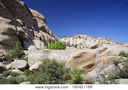 Barker Dam and rock formations within the arid desert ecosystem on the barker dam Trail within Joshua Tree national Park in Joshua Tree California.