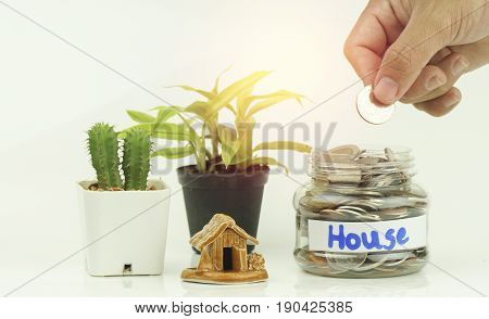 hand put money coins in bottle and home concept in house finance