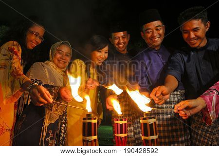 MALACCA MALAYSIA - SEPTEMBER 10 2008 : Men and woman light up the Malay tradition oil lamp or pelita during Hari Raya celebration.