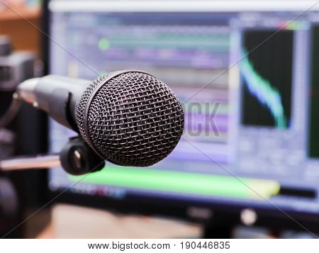 Microphone on the background of the computer monitor. Home recording Studio. Close-up. The focus in the foreground. Blurred background. Software for recording and editing sounds.