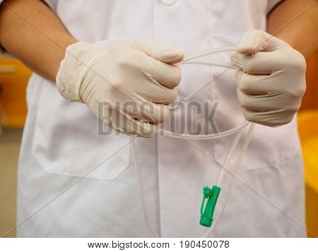 Close-up detail of a physician holding a nasogastric tube with gloved hands. Healthcare and medical equipment concept.