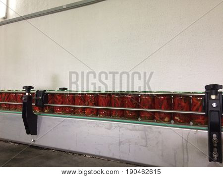 Working process of the production of Preserved red hot chili peppers on cannery. Pasteurization of cans. Movement on the conveyor.