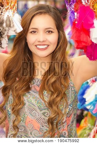 Beautiful smiling young woman hiding behind a colorful catchdreamer, in colorful market fabrics background.
