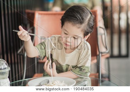 Cute Asian chid eating Spaghetti Carbonara in restaurantvintage fiter