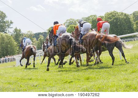 STOCKHOLM SWEDEN - JUNE 06 2017: Side rear view of jockeys riding race horses in a curve at Nationaldags Galoppen at Gardet. June 6 2017 in Stockholm Sweden