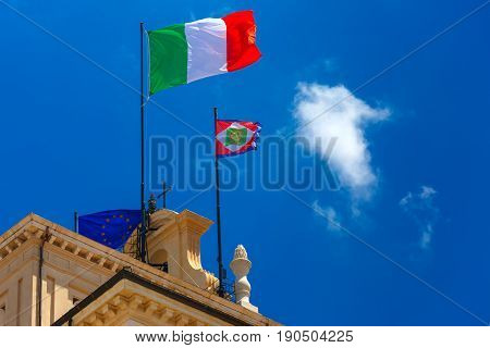Beautiful large waving the flag of Italy and Italian Presidential pennant over Quirinal Palace against the blue sky, Rome, Italy.