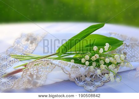 Lily of the valley bouquet on the table with the cloth napkins.