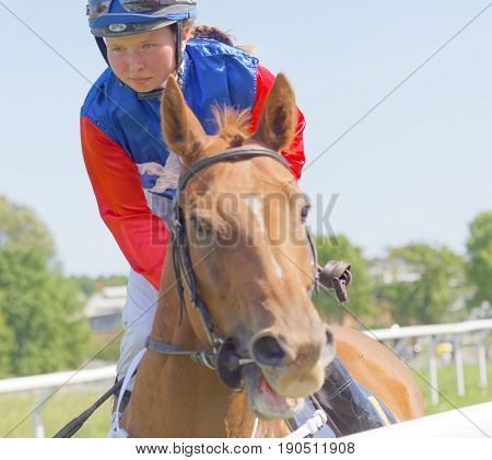 STOCKHOLM SWEDEN - JUNE 06 2017: Closeup of a female jockey riding a brown arabian race horse at Nationaldags Galoppen at Gardet. June 6 2017 in Stockholm Sweden