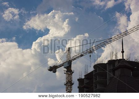 high construction crane build unfinished city housing against the background of the blue sky and clouds. horizontal shot