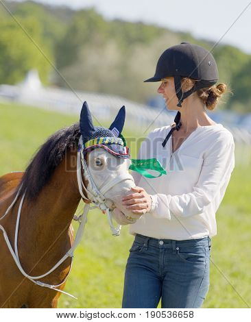 STOCKHOLM SWEDEN - JUNE 06 2017: Woman strokes a cute pony gallop race horses on the muffle at Nationaldags Galoppen at Gardet. June 6 2017 in Stockholm Sweden