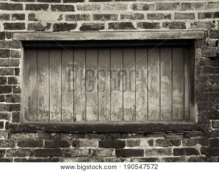 boarded up wondow with peeling paint in an old brick building