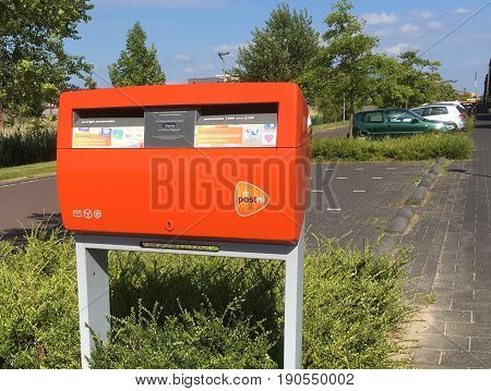 Almere Poort, Flevoland, The Netherlands - June 10, 2017: Orange PostNL mailbox standing on the side of a street in Almere . PostNL is the Dutch postal service.
