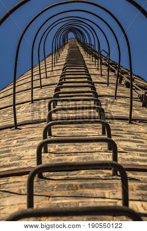 Low view of the ladder of an old factory's chimney
