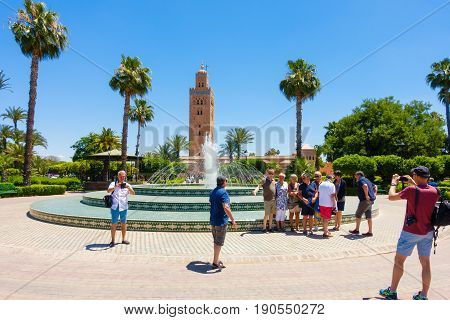 Marrakech Morocco - May 12 2017: A group of tourists taking photos of each other in front of the fountain in Koutoubia Gardens with the Koutoubia Mosque in the background.